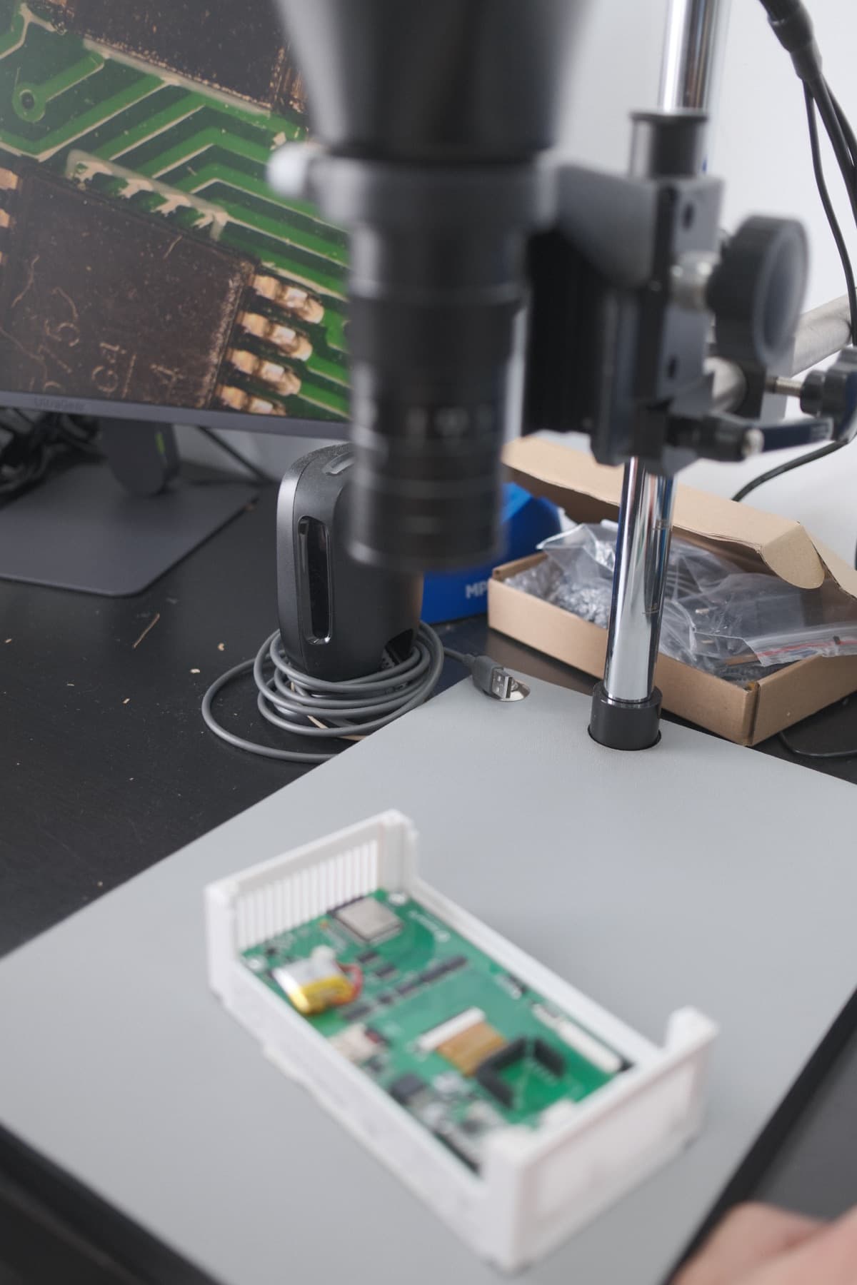 Inspección de una placa de circuito impreso bajo microscopio en el banco de trabajo de DCMI