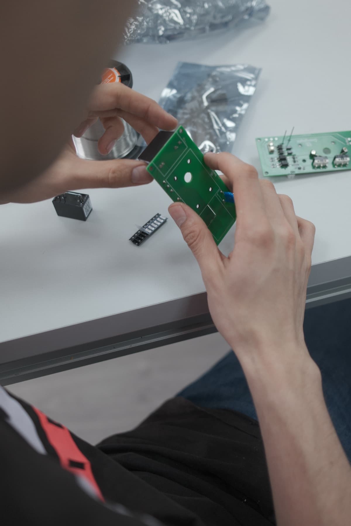 Manos revisando una placa de circuito con componentes sobre el banco de trabajo